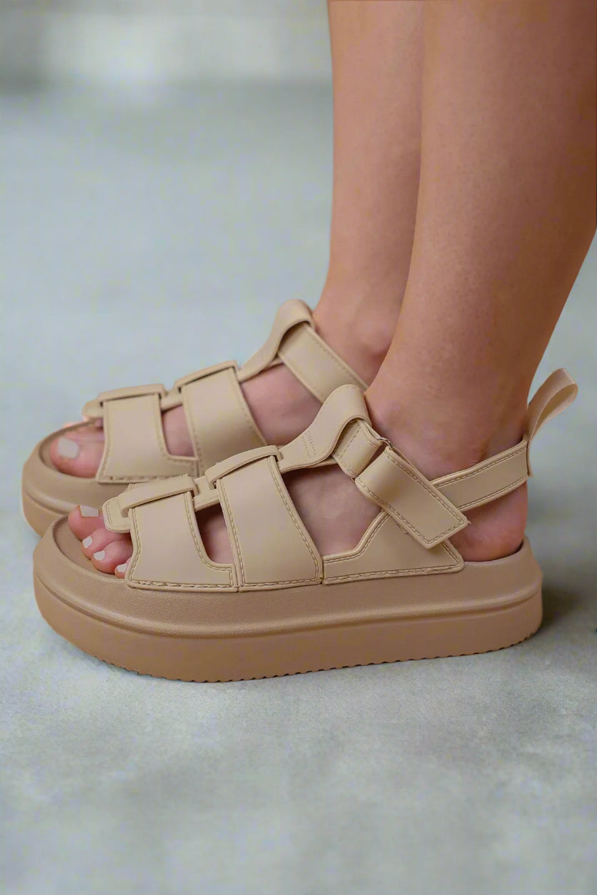 Beige sandals worn on a beige background